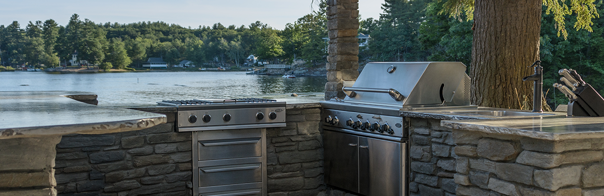 Stone outdoor kitchen with grill and sink in Madison, WI